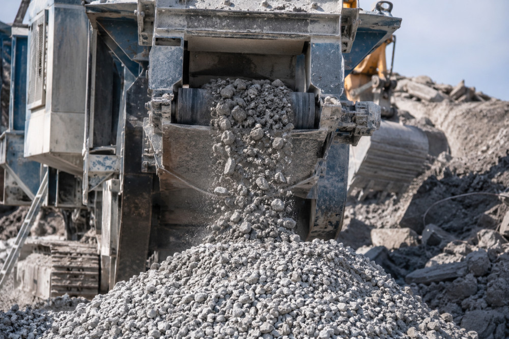 A concrete crushing machine in operation, with crushed aggregate being poured out from the conveyor belt.